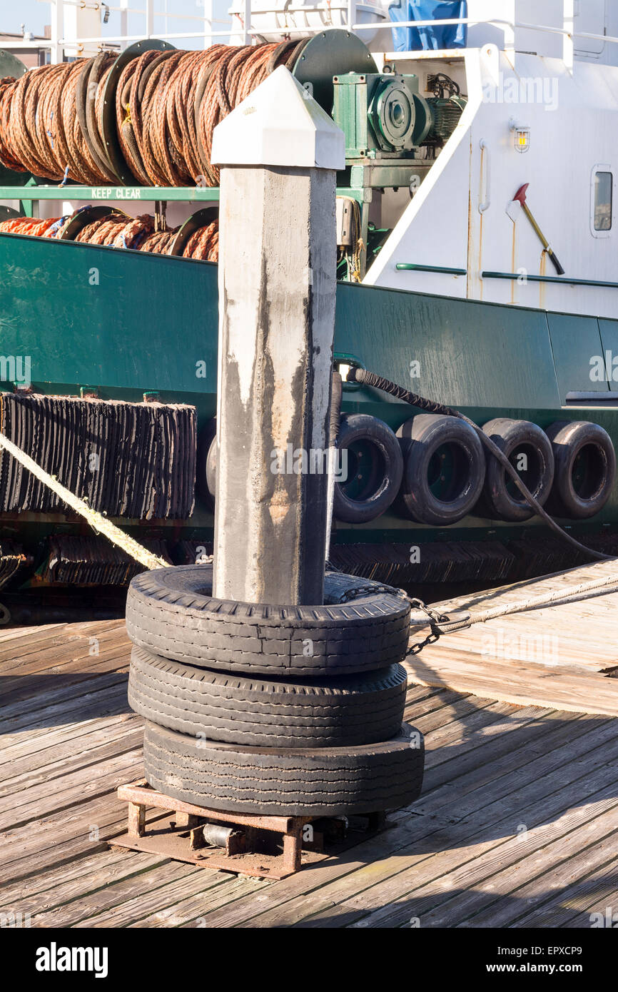 A dock pylon with used tires around it are used as means to tie up barges as they rest in their slips Stock Photo