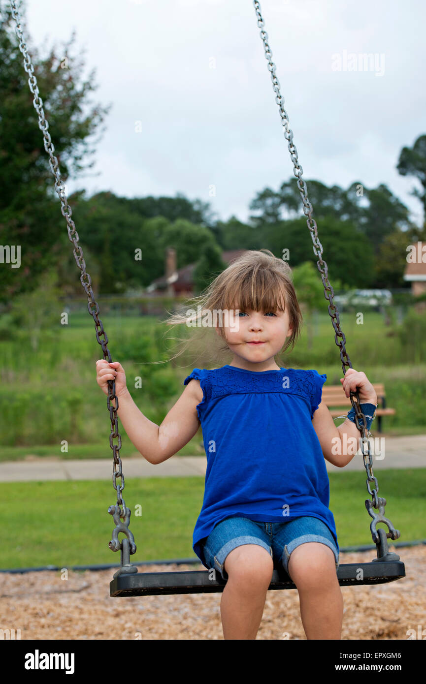 Young girl swings at an outdoor playground park Stock Photo