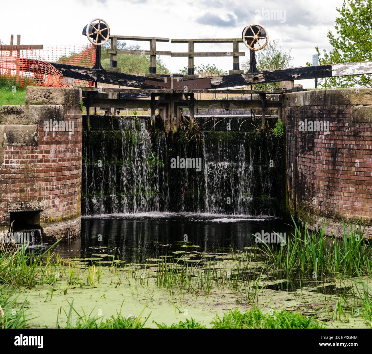 Black, closed lock gates with opening mechanism holding back water on canal Stock Photo Alamy