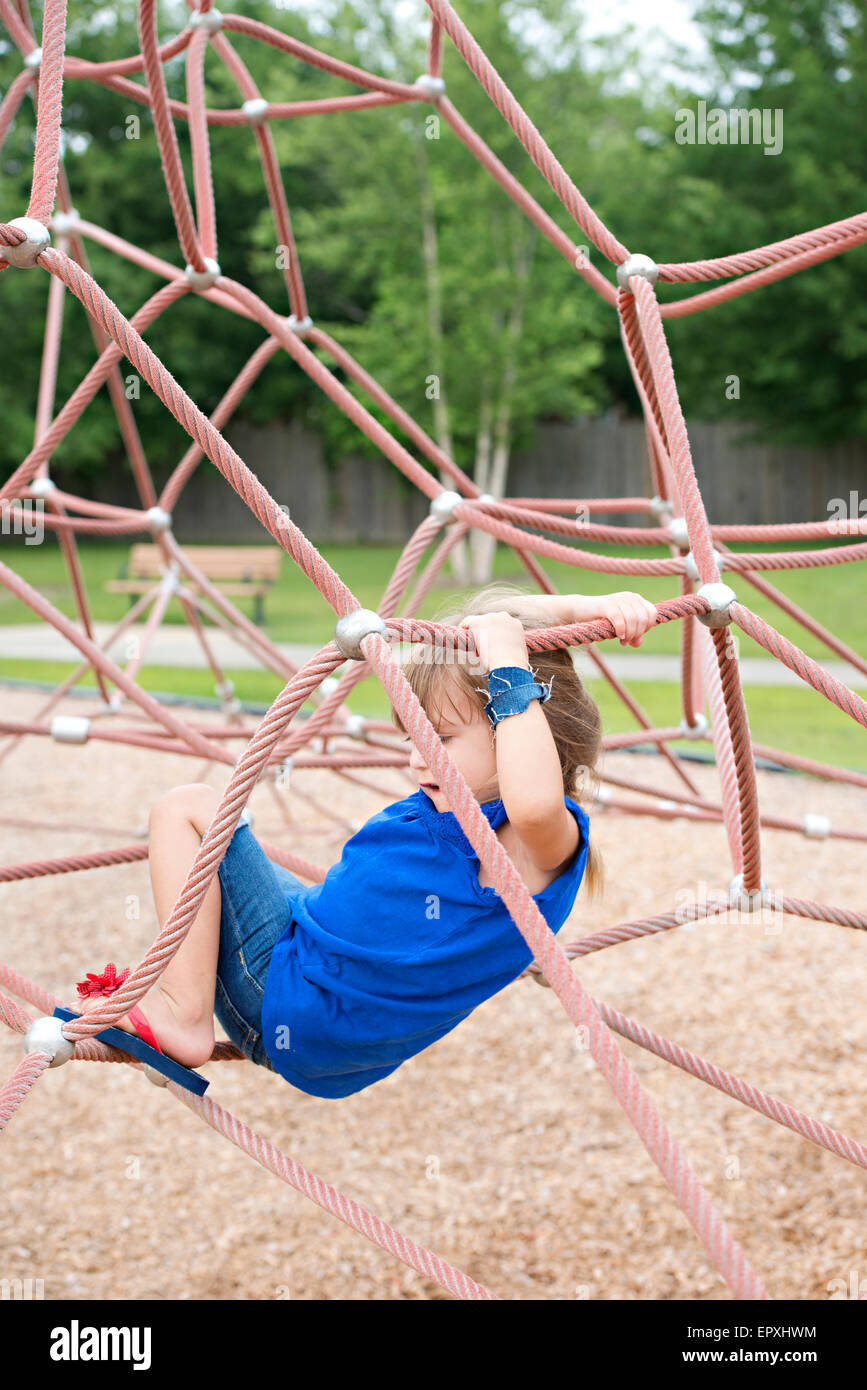 Young girl plays on a rope climbing structure at an outdoor park