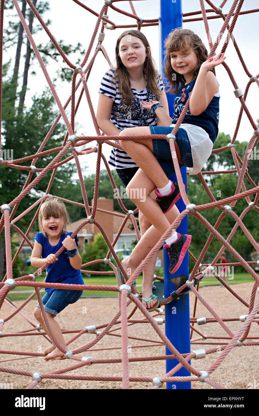 Siblings play on a rope climbing jungle gym at an outdoor park playground Stock Photo