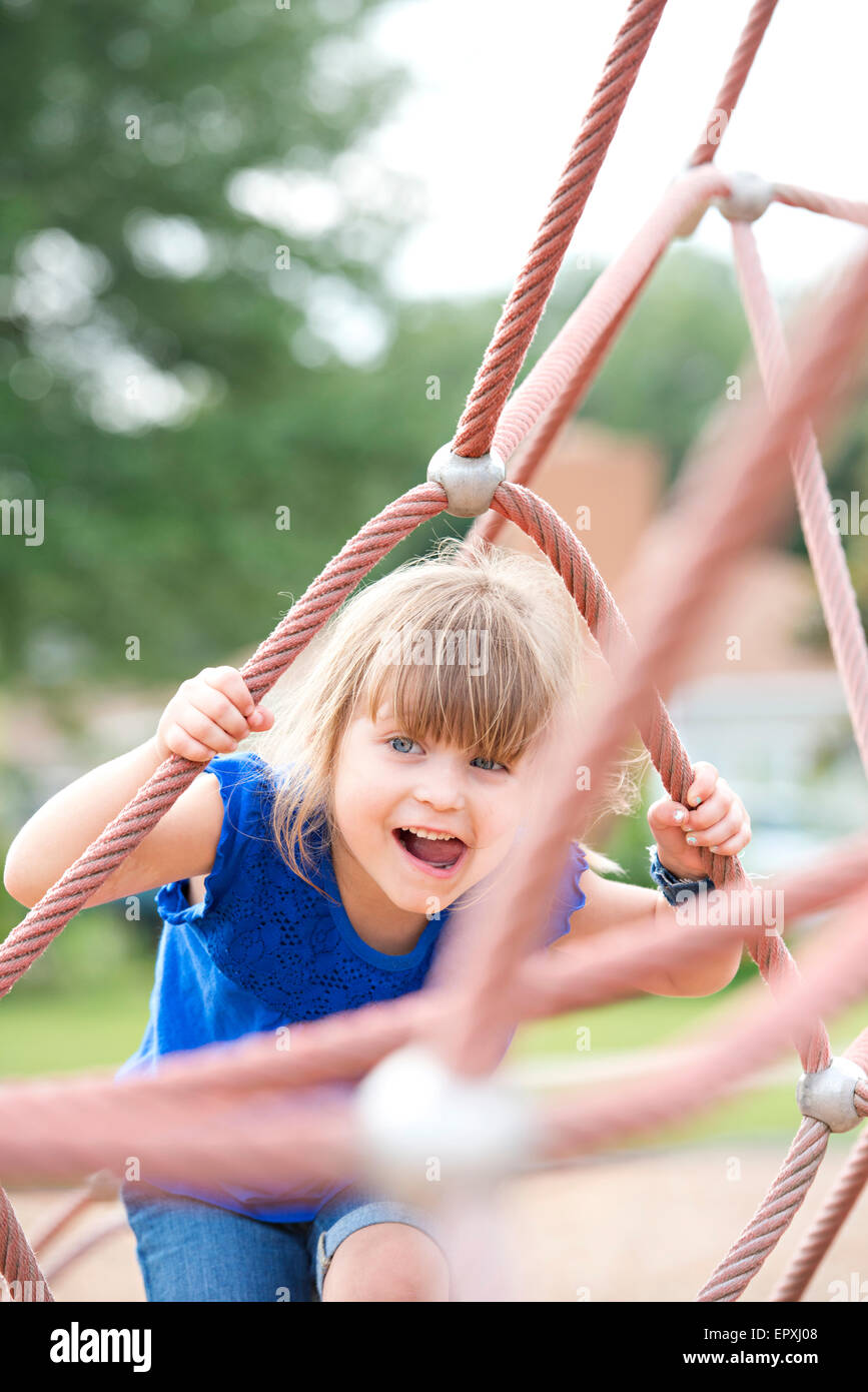 Young girl plays on a rope climbing structure at an outdoor park
