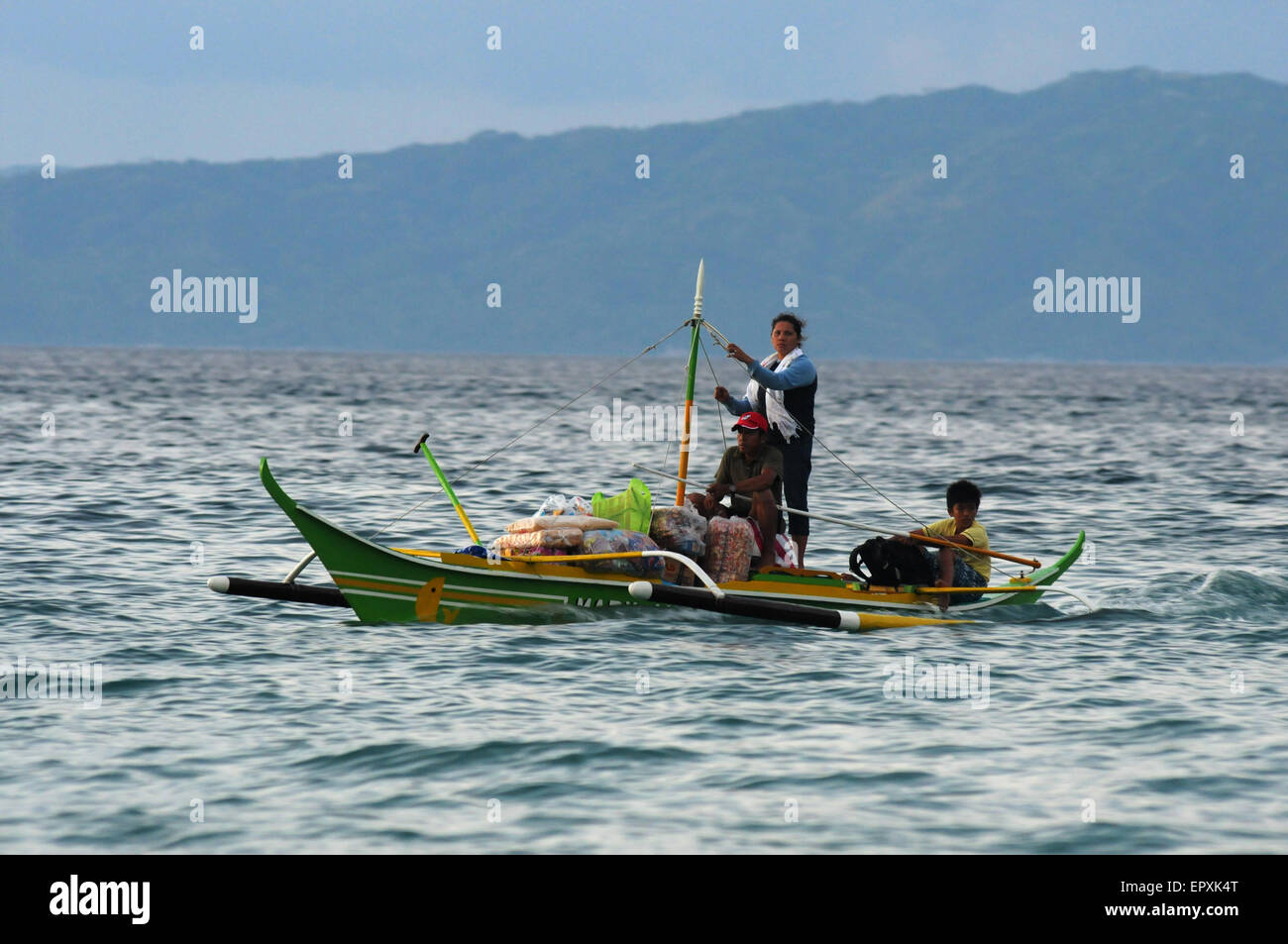 A Filipino fisherman family in a light boat loaded with bags near the ...