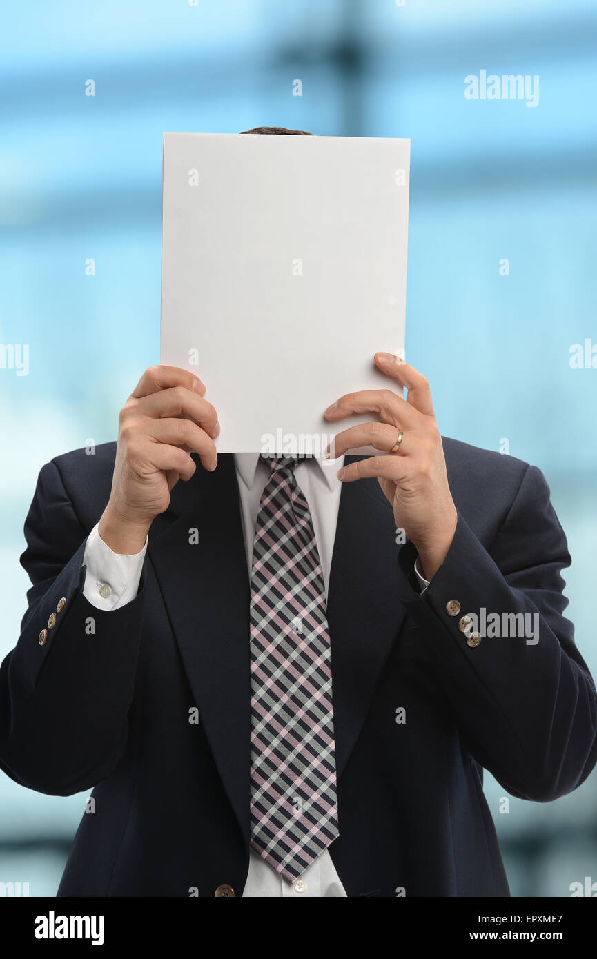 Businessman hiding behind papers inside office building Stock Photo