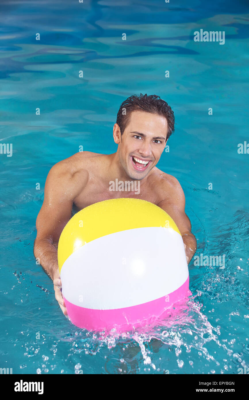Happy man with water ball playing in a swimming pool in summer Stock Photo