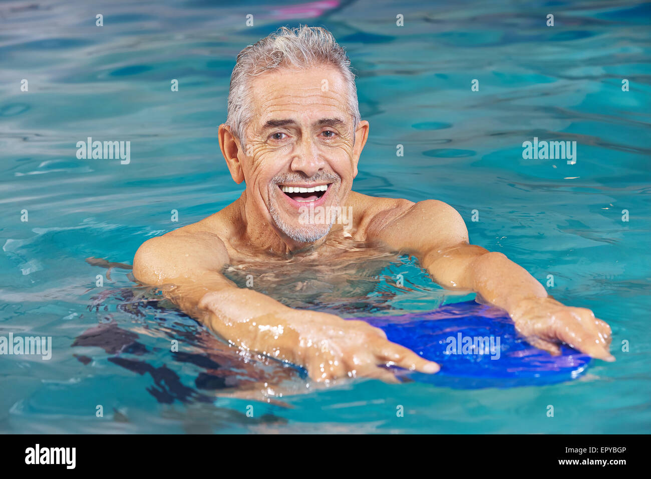 Happy senior man with kickboard in water of swimming pool Stock Photo
