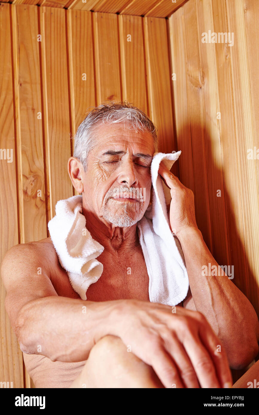 Old man with towel sweating in sauna of spa hotel Stock Photo