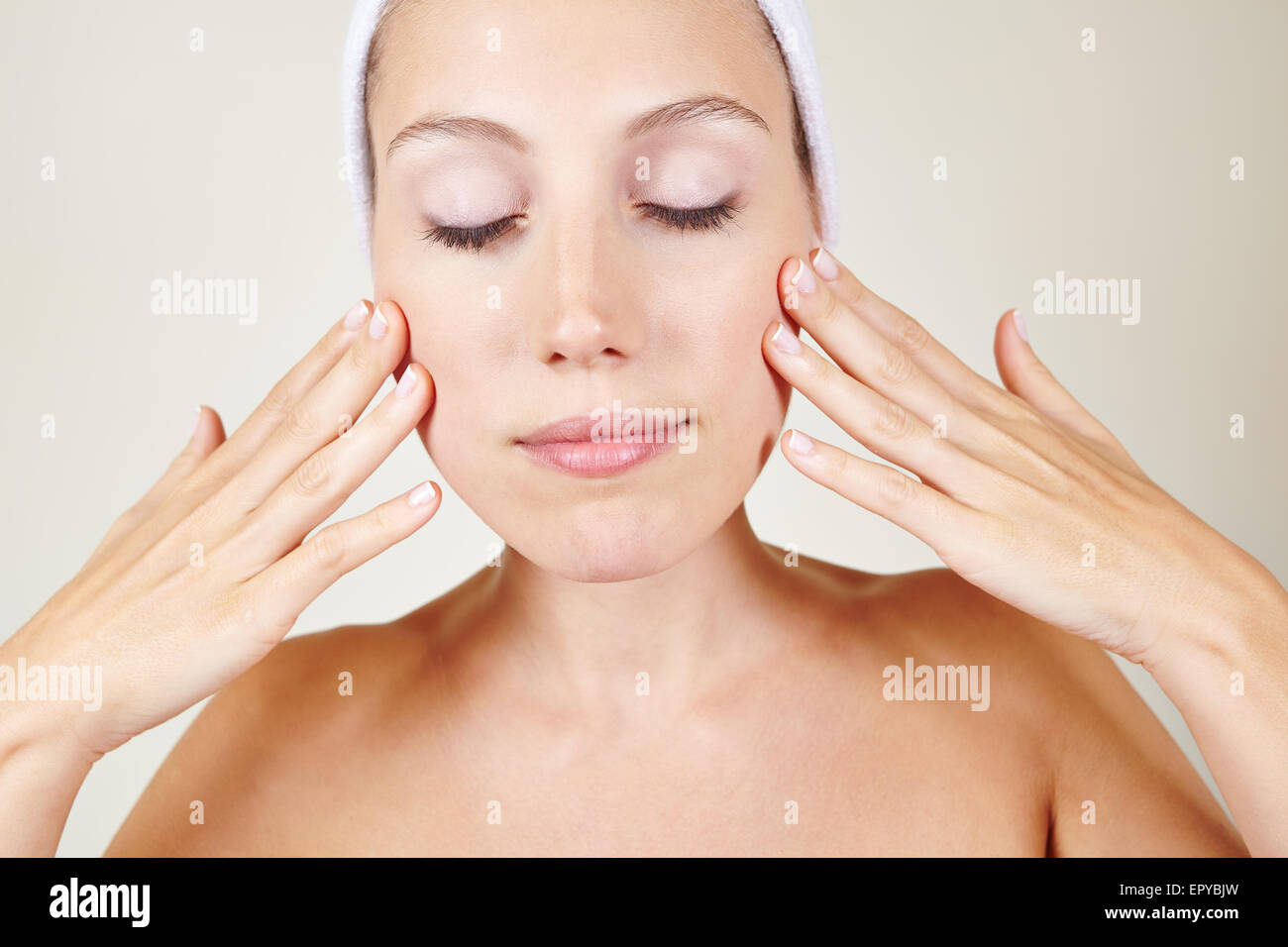 Attractive young woman in spa putting skin lotion on her face Stock