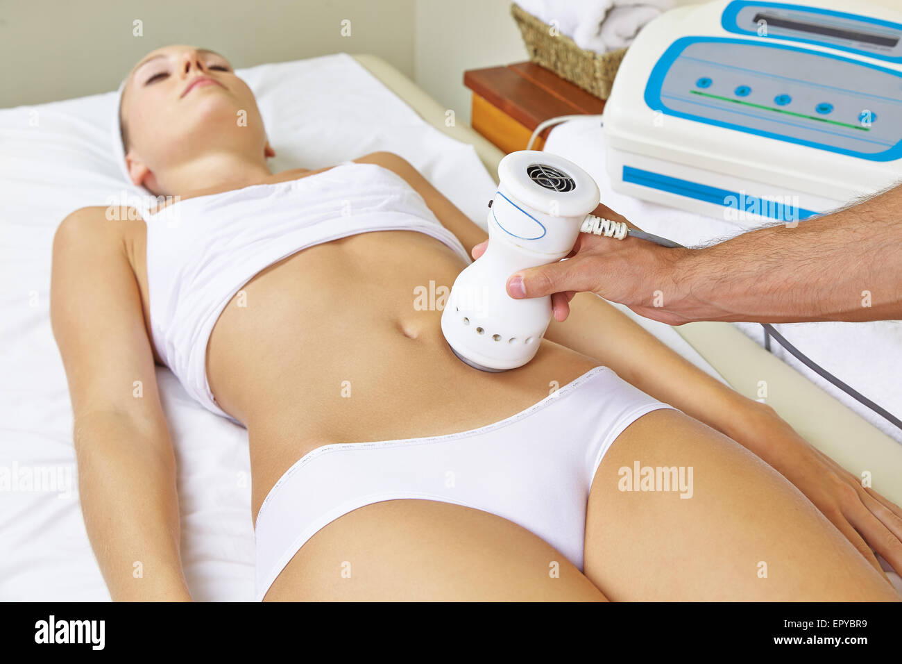 Woman receiving electric massage on stomach for muscle training in spa Stock Photo