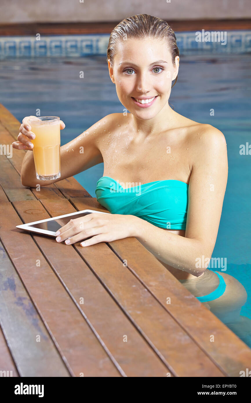 Smiling woman using a tablet computer in a swimming pool in summer Stock Photo