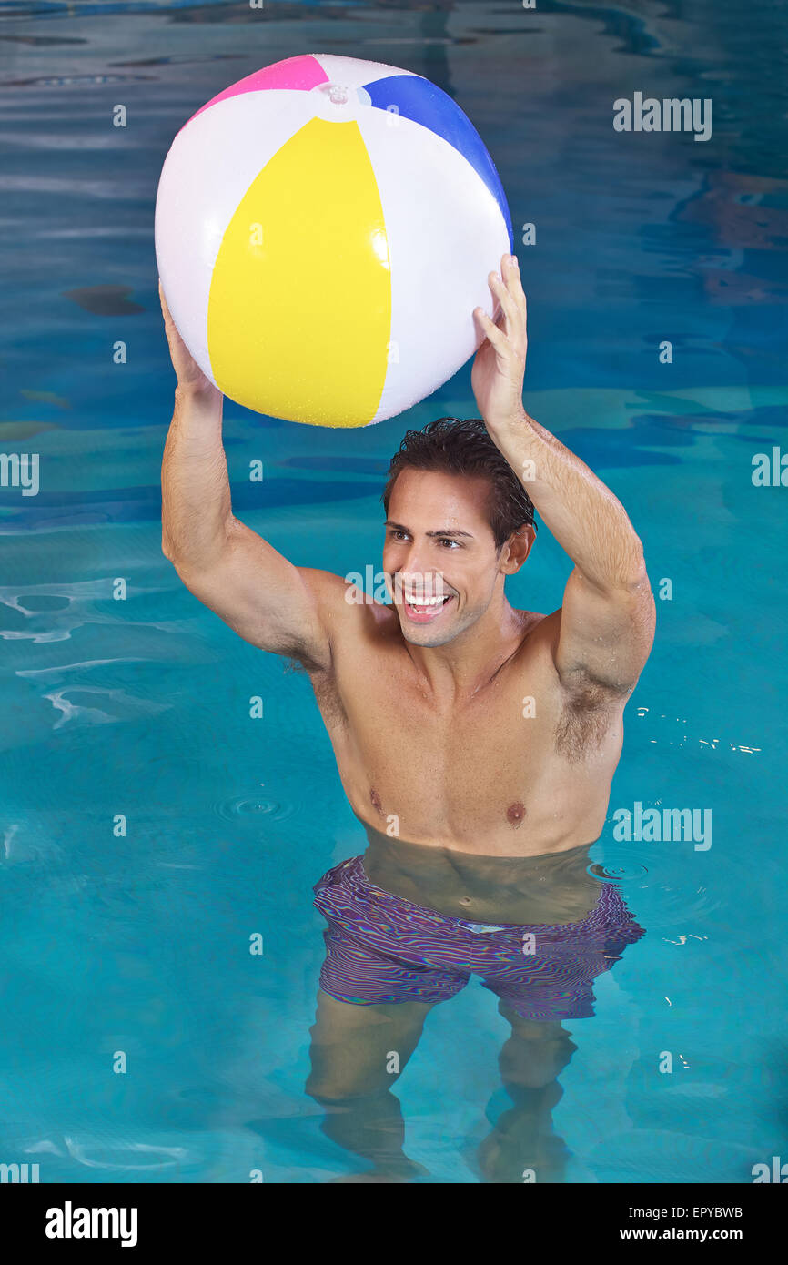 Happy man in swimming pool playing with a water ball Stock Photo
