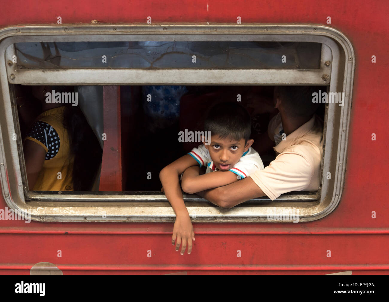Boy Looks Out Window of Crowded Train, Colombo Fort Station, Sri Lanka Stock Photo