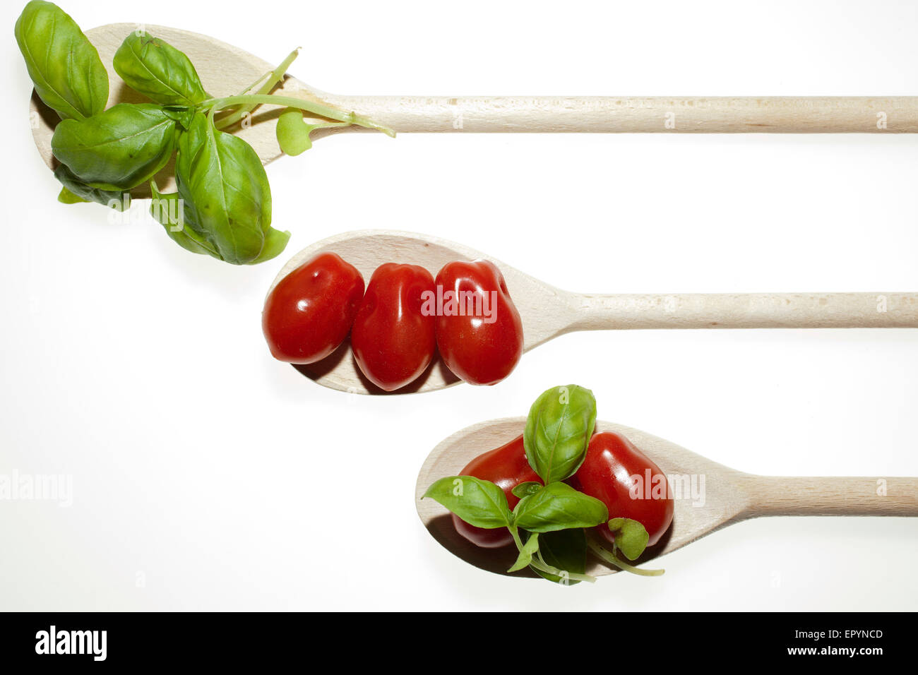 tomatoes, basil on wooden spoon in white background Stock Photo - Alamy