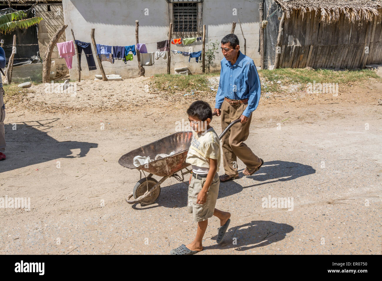 Man pushing wheelbarrow with young boy walking beside in Guatemala Stock Photo