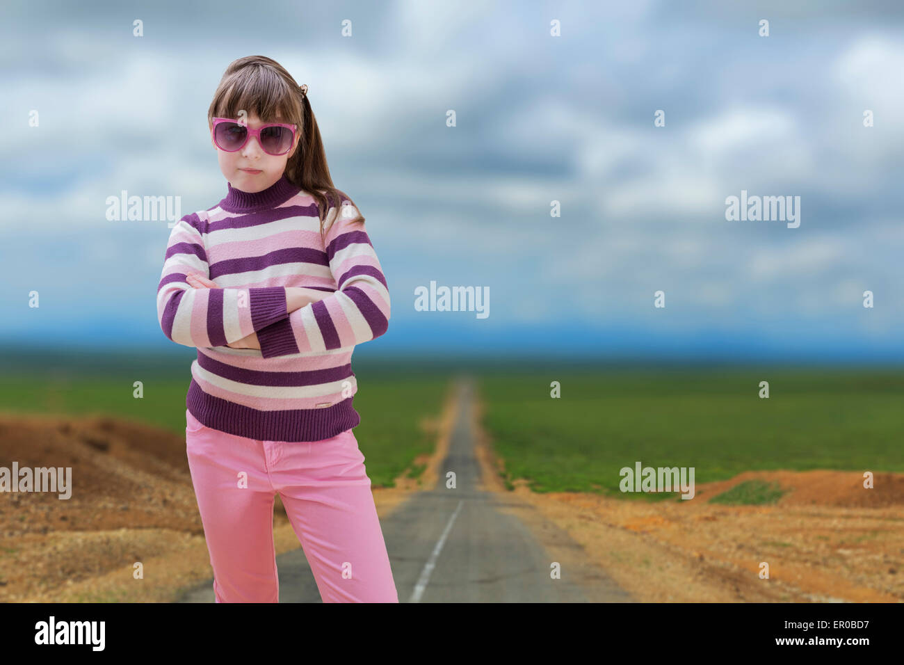 Teenage girl in pink wearing sunglasses with road in background Stock Photo