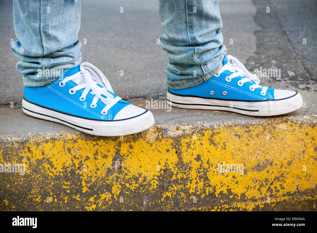 Brand new blue shoes and yellow concrete edge, urban walking theme ...