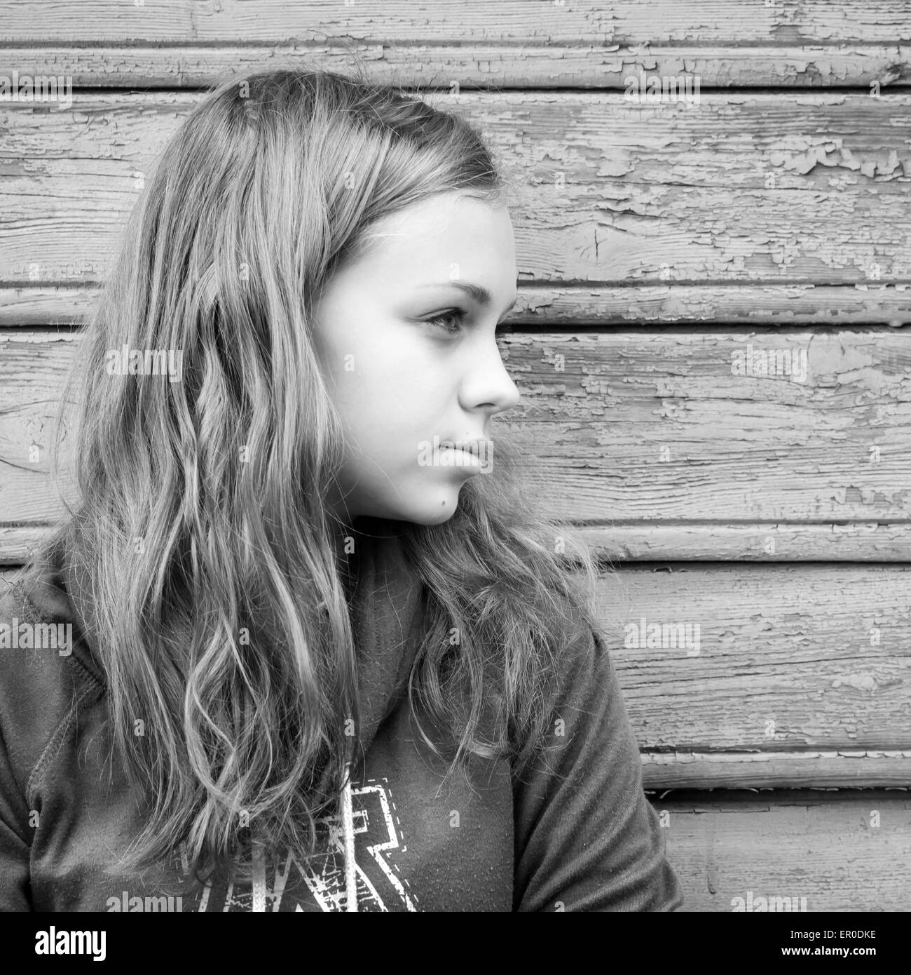 Beautiful blond Caucasian girl  teenager, closeup outdoor portrait over rural wooden wall Stock Photo