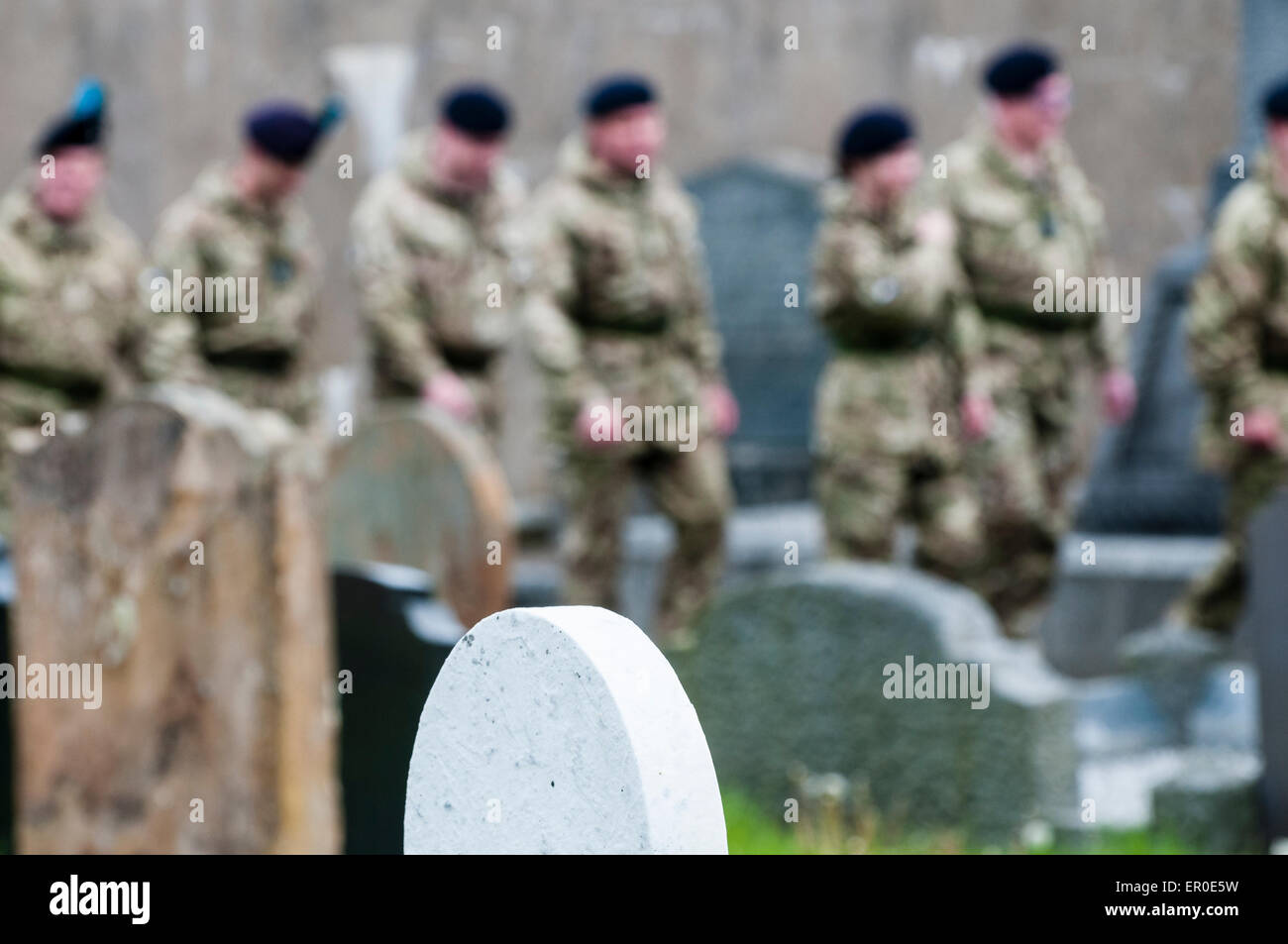 Soldiers walk among gravestones in a graveyard Stock Photo