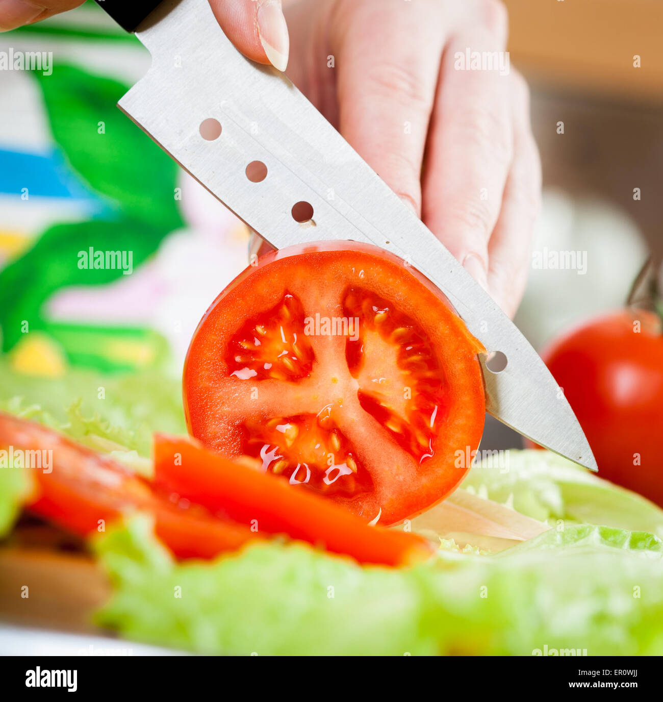 Woman's hands cutting fresh tomato on kitchen Stock Photo