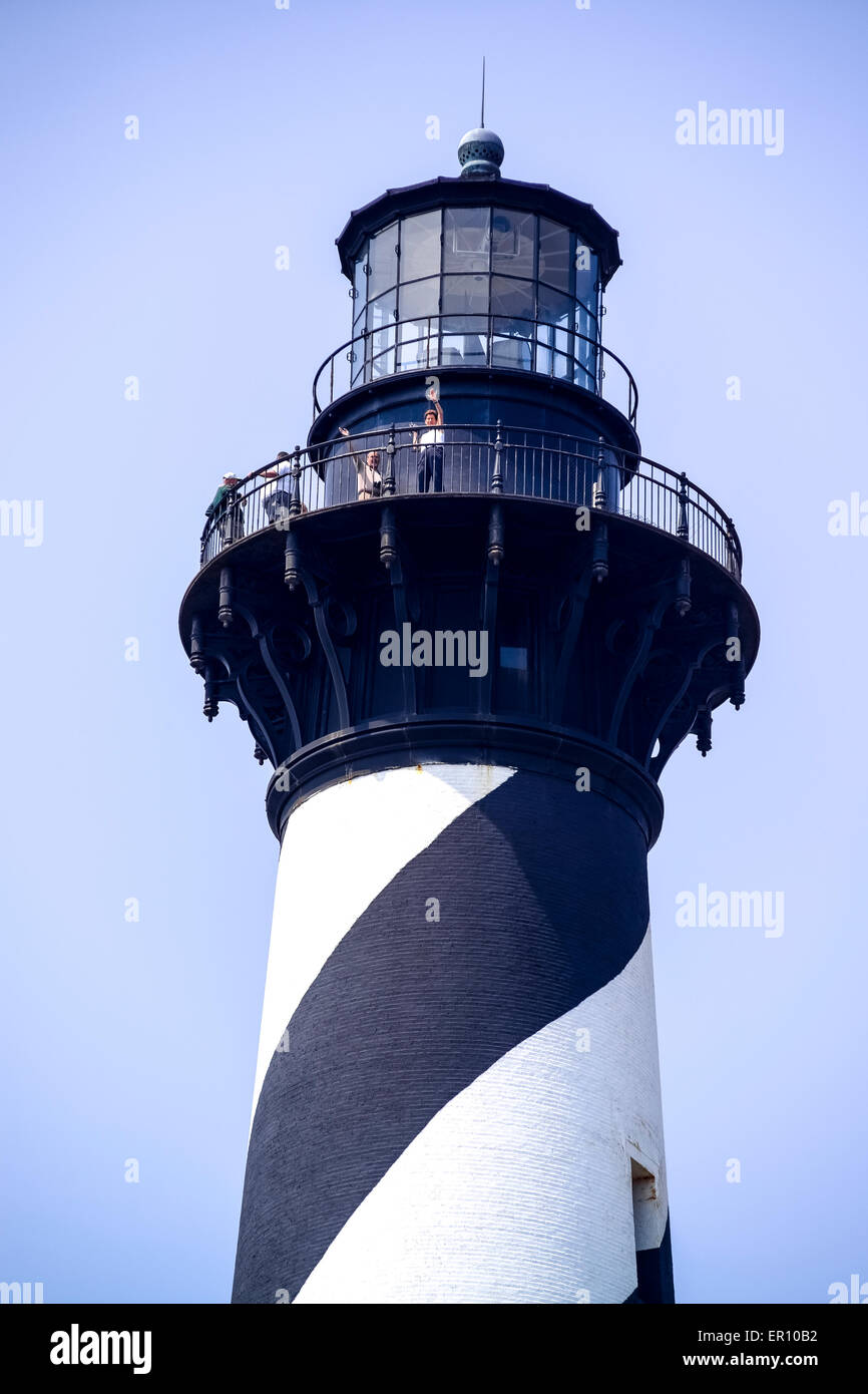 Two visitors wave from the top of the historic 208-foot Cape Hatteras Light Station in the Outer Banks of North Carolina, USA. Stock Photo