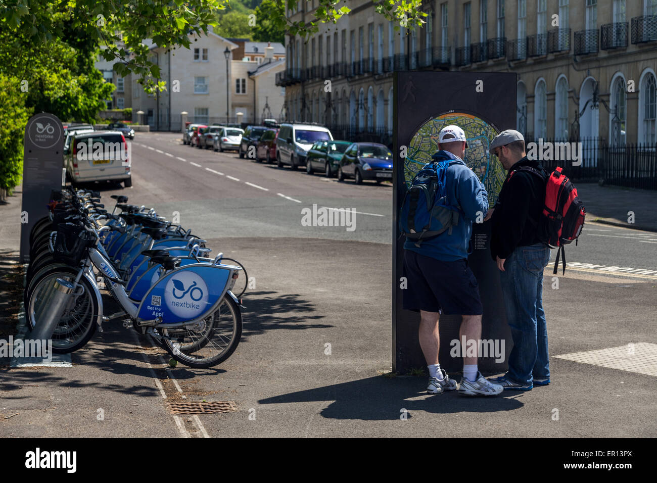 Two tourist men reading an information map notice next to electric hire bikes in City of Bath, UK Stock Photo