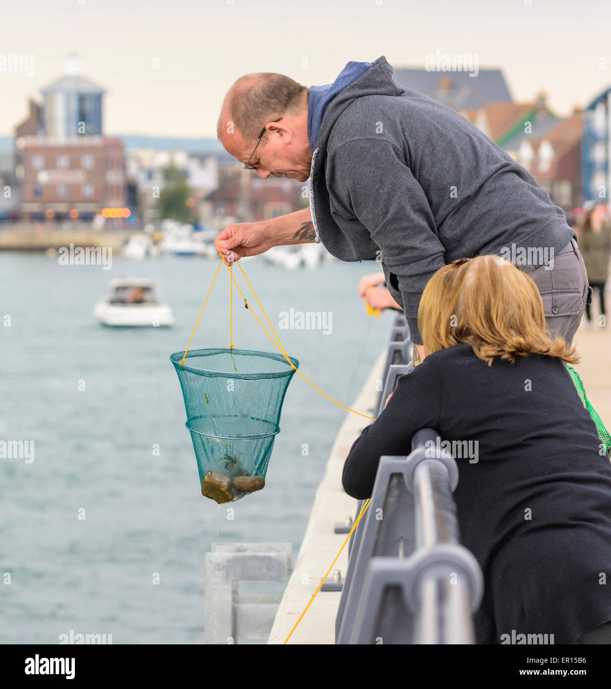 Man with a net crab fishing by the river in Littlehampton, West Sussex, England, UK. Stock Photo