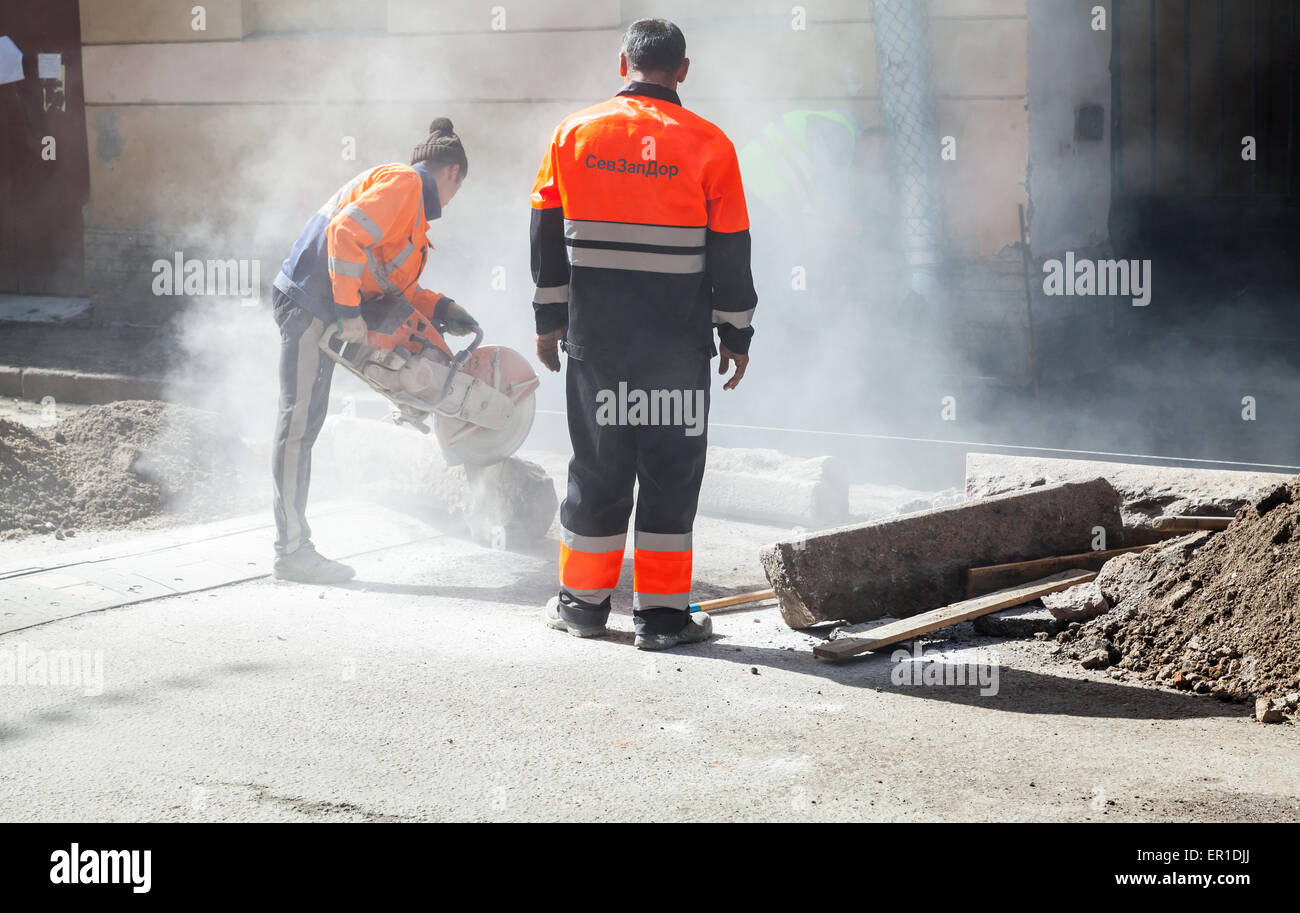 Saint-Petersburg, Russia - May 32, 2015: men at work, urban road under construction, sawing of a roadside border stones Stock Photo