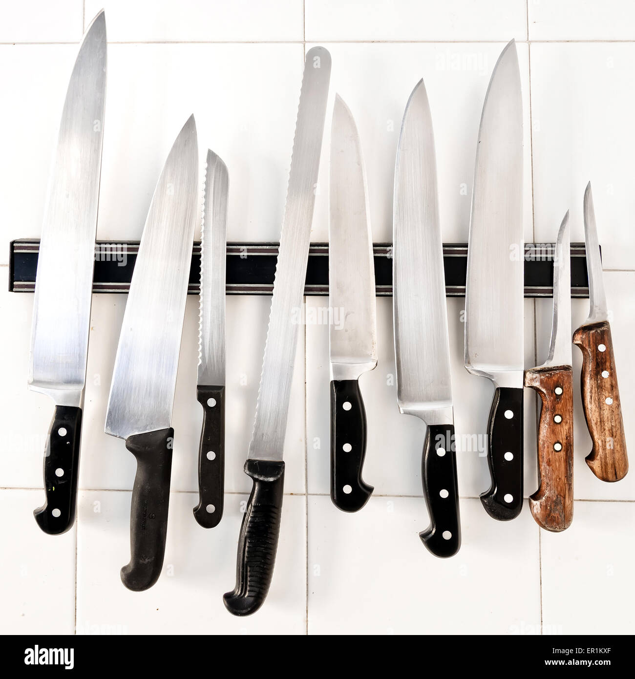 Set of knives on holder on white tiles Stock Photo Alamy