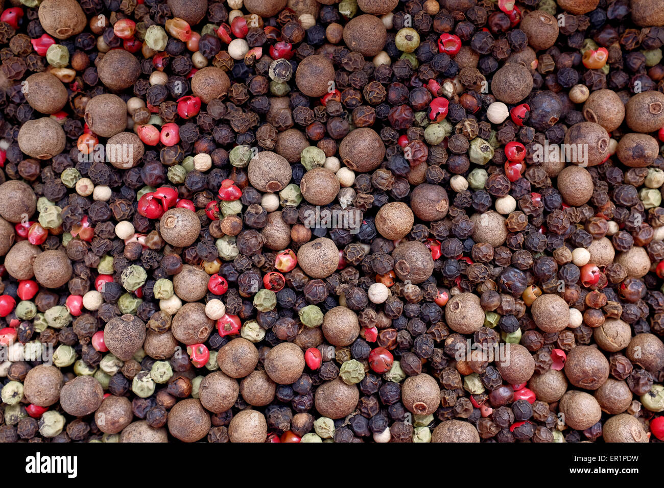 Mixed peppercorns - black, white, pink, green, pimento - as an abstract background texture Stock Photo