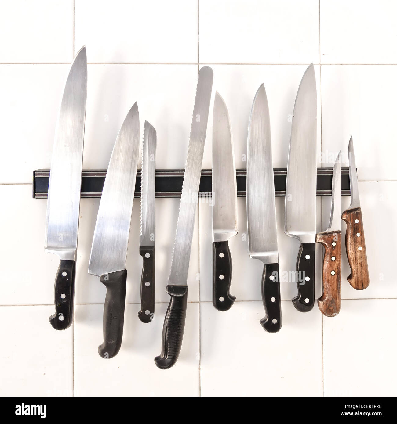 Set of knives on holder on white tiles Stock Photo Alamy