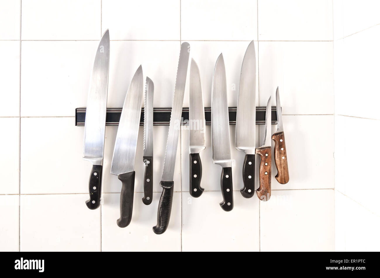 Set of knives on holder on white tiles Stock Photo Alamy