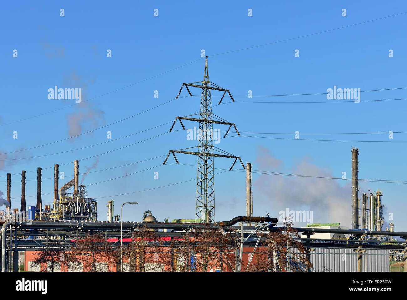 Panorama of industrial zone with pipes and steam on blue sky and electric poles Stock Photo