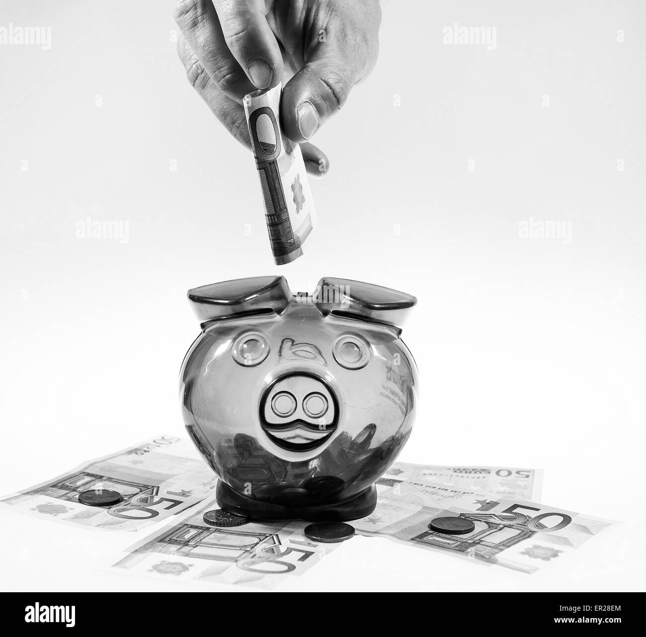 Hand is putting euro currency note into the money box (piggy). Euro