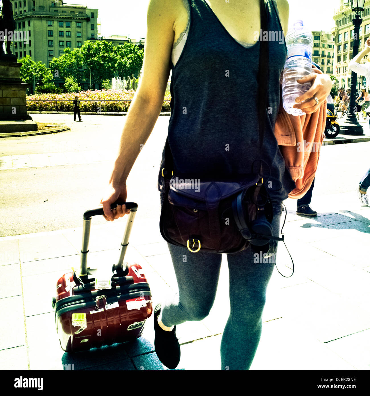 Woman walking with a wheeled suitcase. Barcelona, Catalonia, Spain. Stock Photo