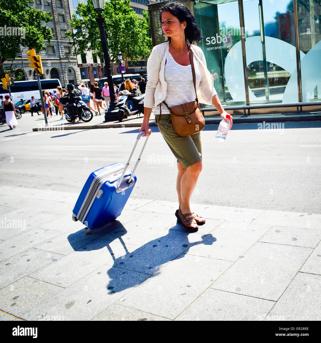 Woman walking with a wheeled suitcase. Barcelona, Catalonia, Spain. Stock Photo