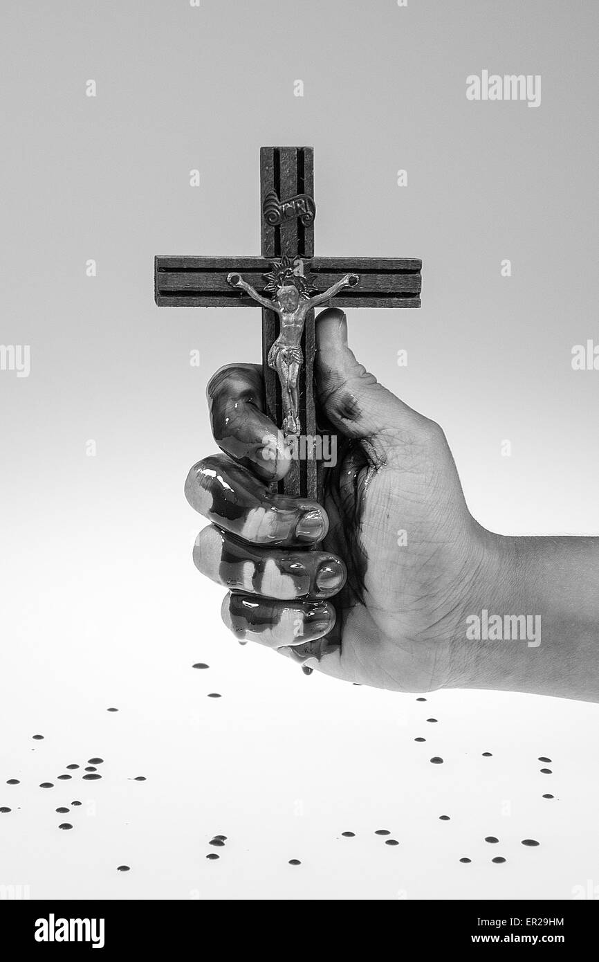 Hand covered with blood is holding a cross, white and grey gradient background. Stock Photo