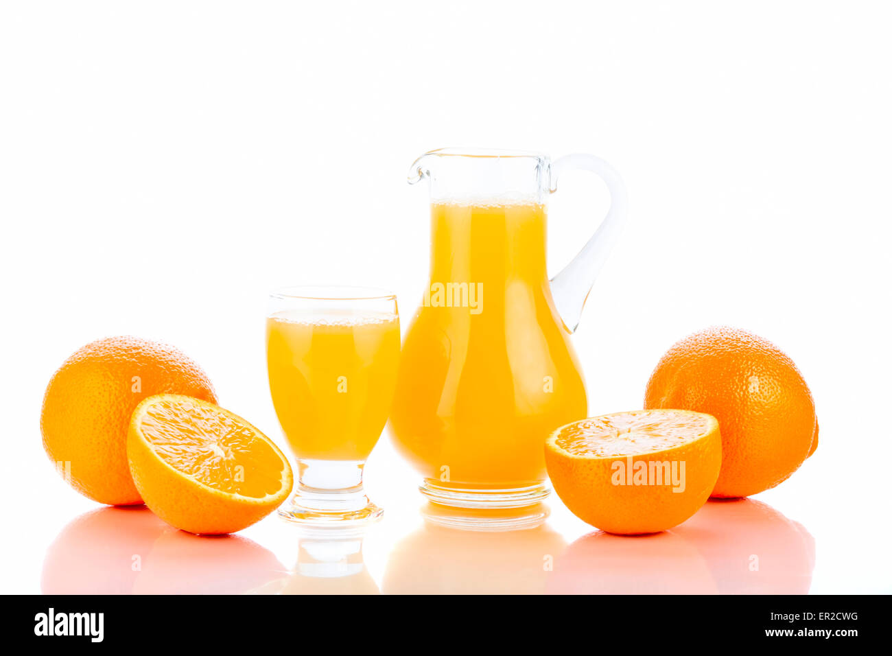 Orange juice in pitcher and oranges. Isolated on white background Stock Photo