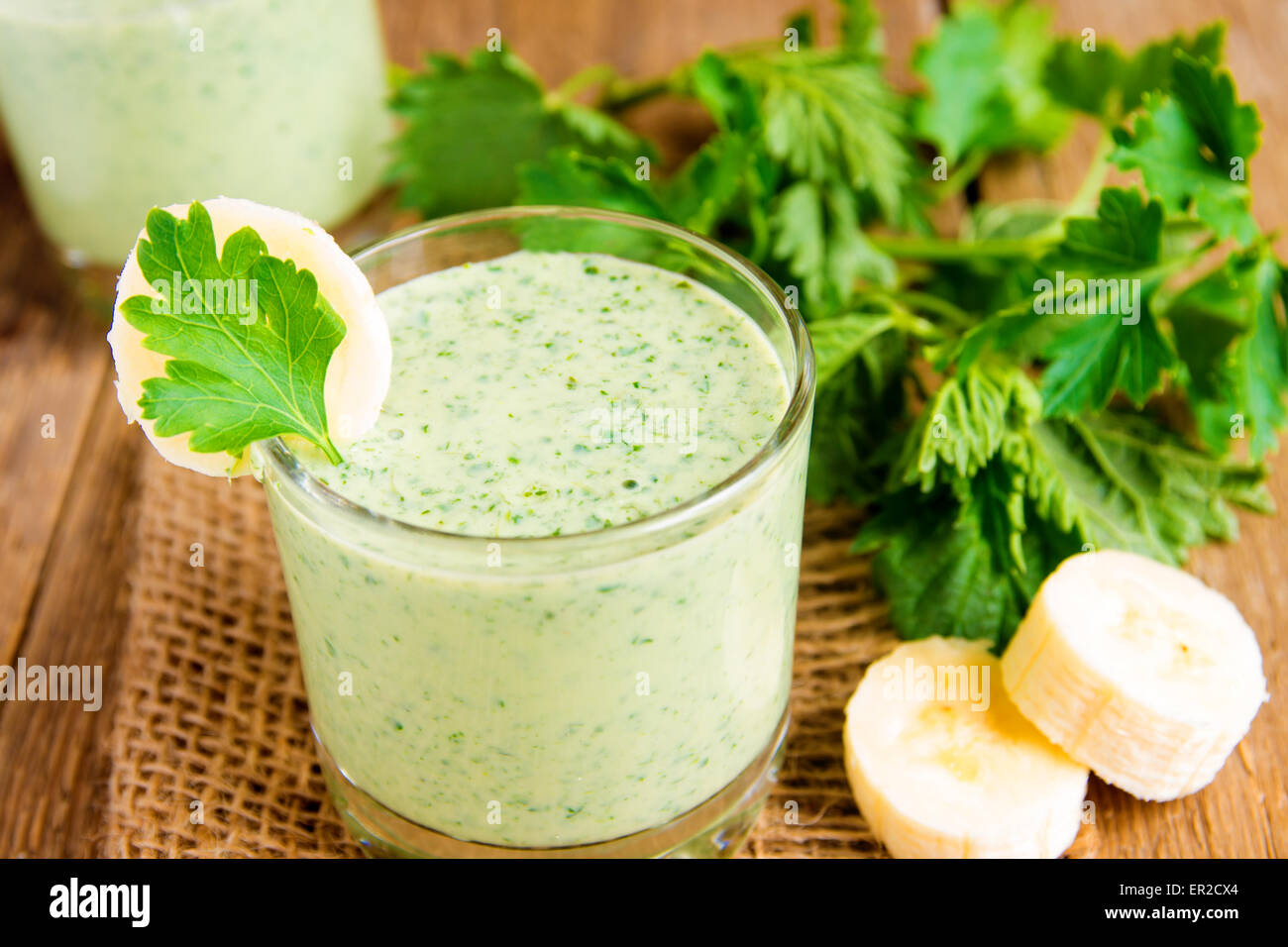 Cold smoothie from banana, yougurt, herbs and vegetables on wooden table, close up horizontal Stock Photo