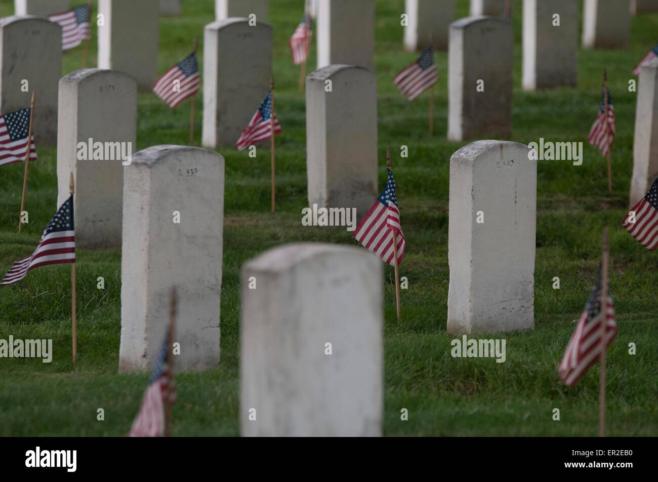 U.S flags in front of grave sites in honor of Memorial Day at Arlington National Cemetery May 21, 2015 in Arlington, Virginia. The Old Guard has conducted Flags-in, when an American flag is placed at every headstone, since 1948. Stock Photo
