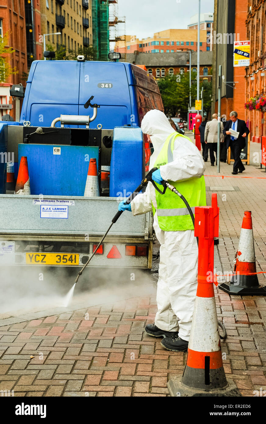 Council worker uses a pressure washer to remove chewing gum from a footpath. Stock Photo