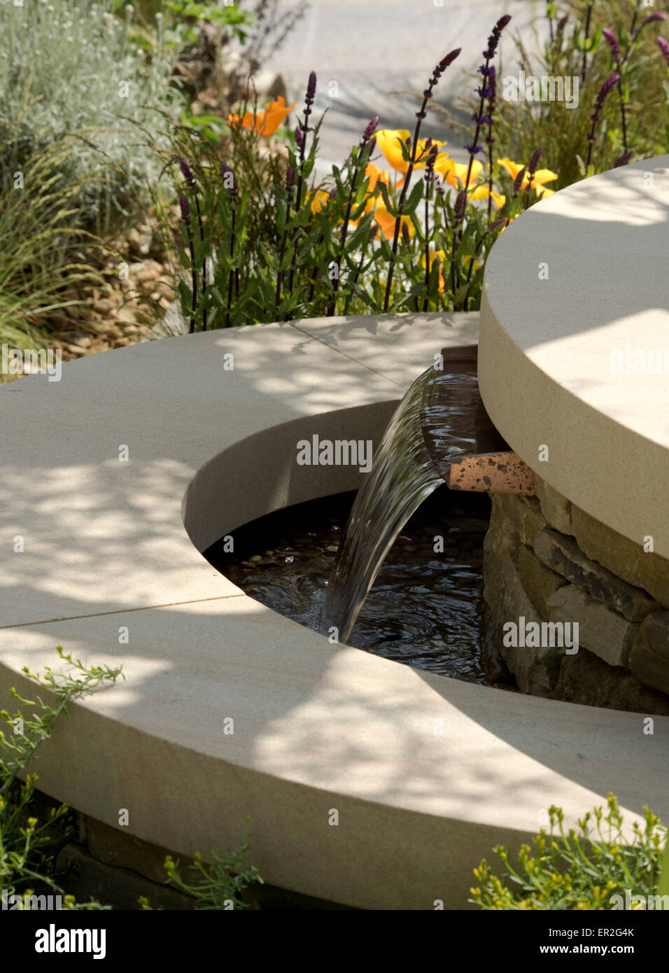 A close-up of a tiered stone fountain in The Royal Bank of Canada Garden designed by Mathew Wilson at The Chelsea Flower Show Stock Photo