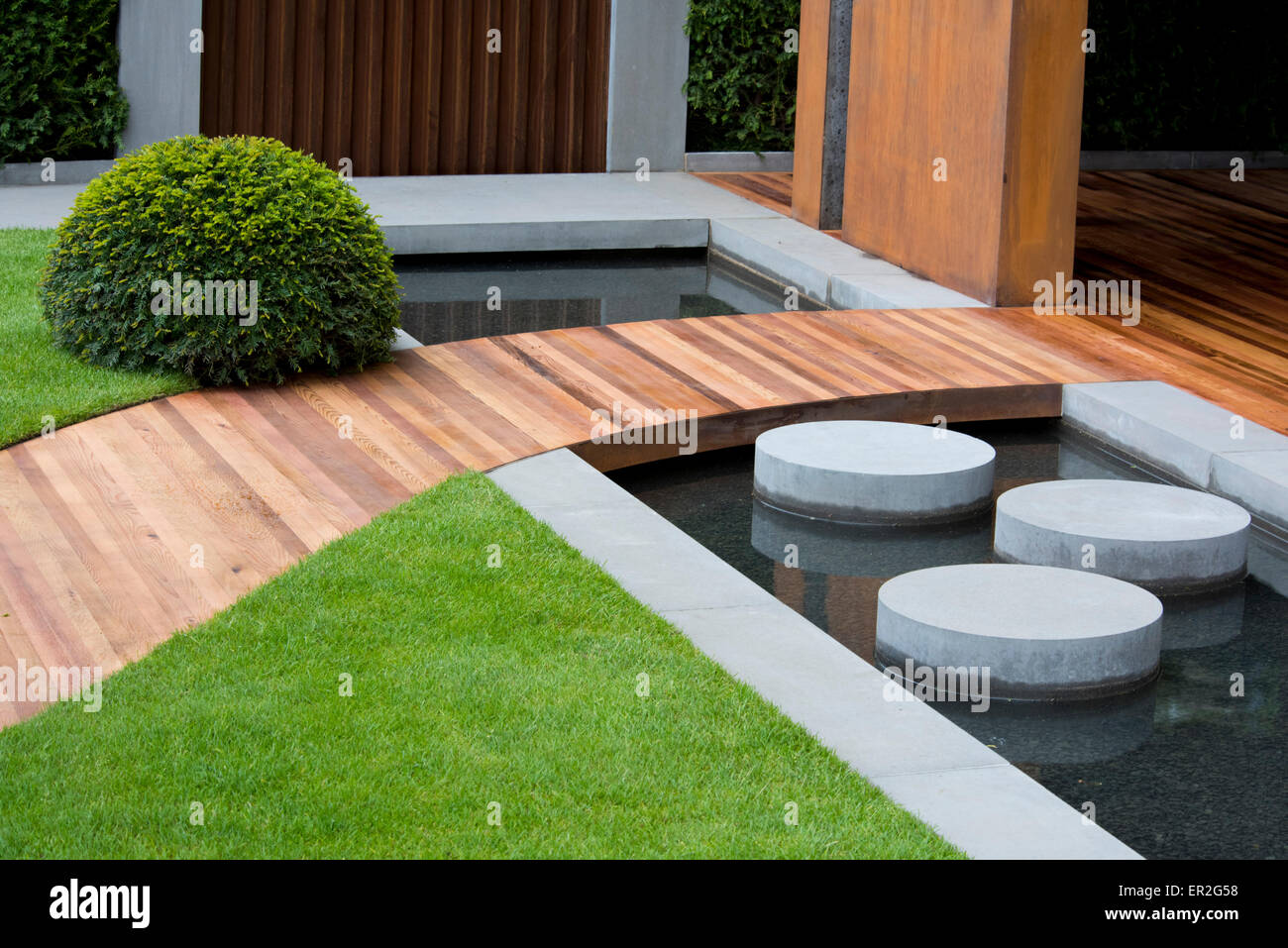 A cedar pathway and stepping stones in a water feature in the Homebase Urban Retreat Garden at The Chelsea Flower Show Stock Photo