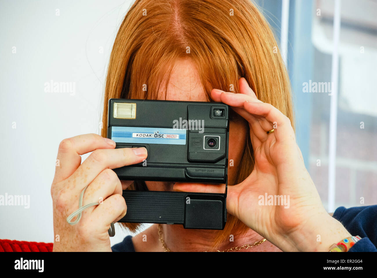 Redhaired woman uses a Kodak Disc camera which were popular during the 1980s. Stock Photo