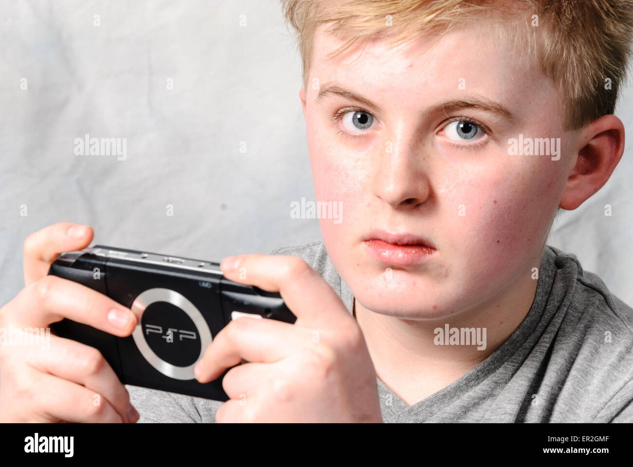 Young boy playing a Sony PSP handheld video game. Stock Photo