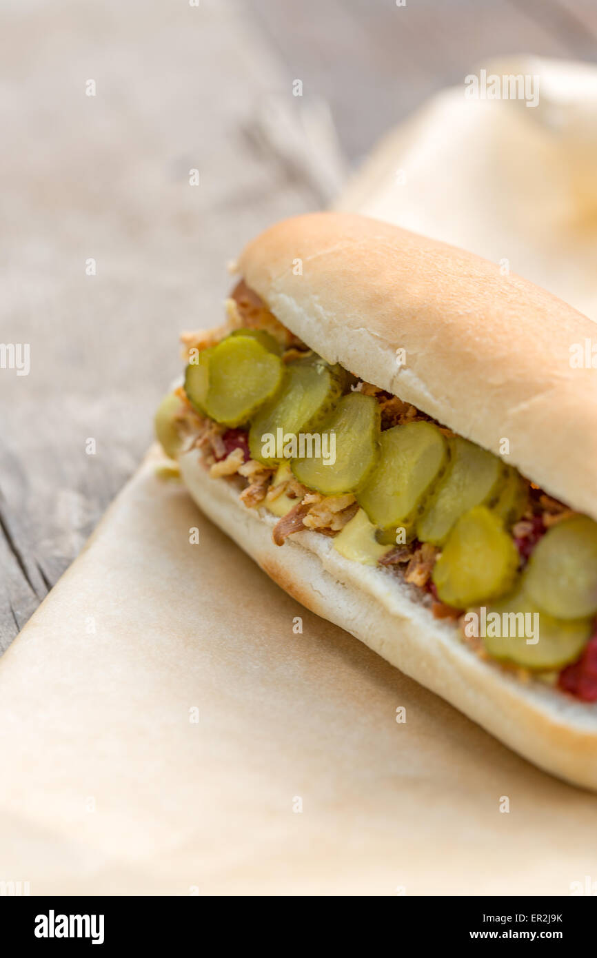 Hot Dog sausage in a bun with roasted onions, pickles, ketchup and mustard on rustic wooden background Stock Photo