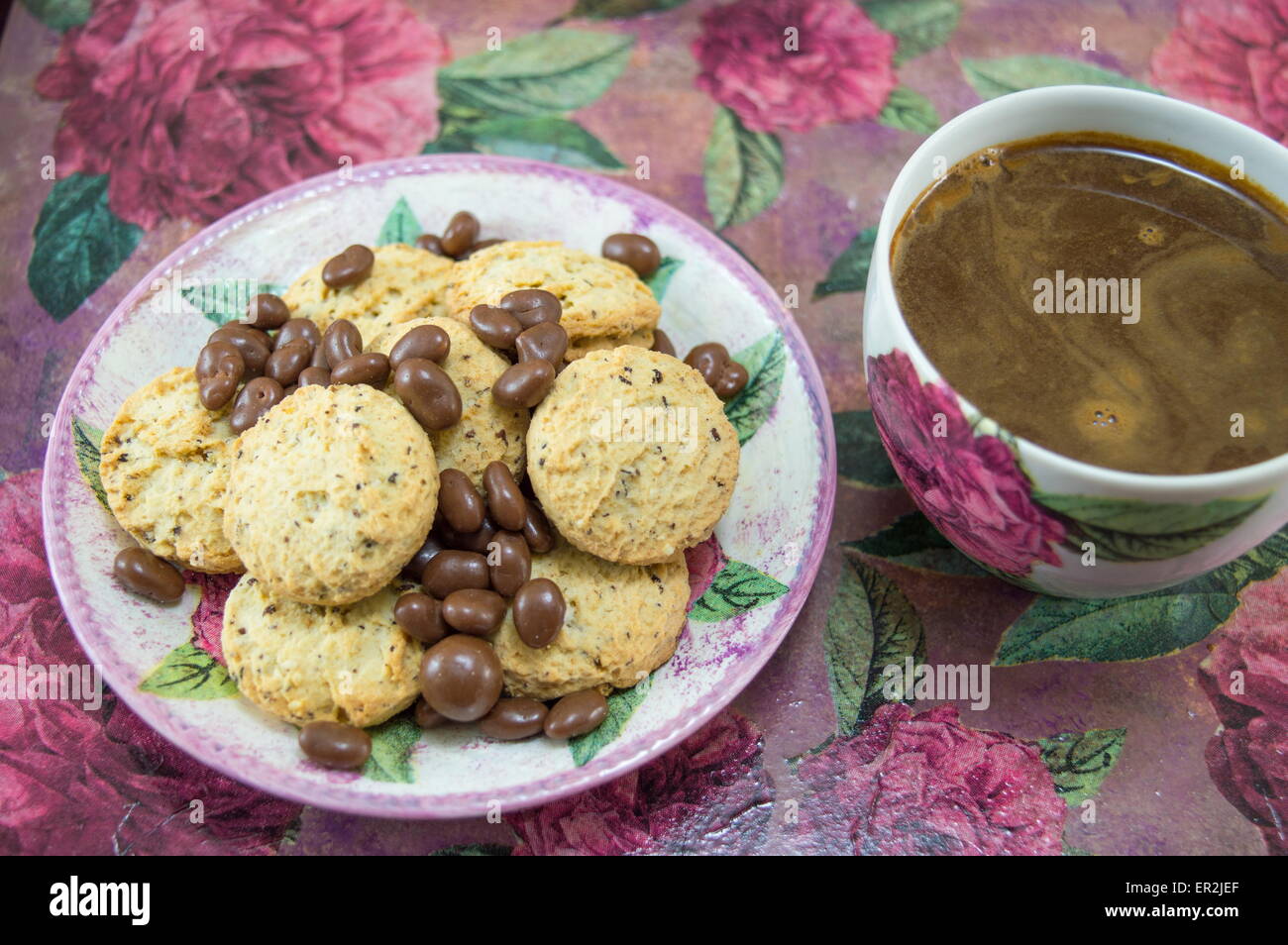 Integral cookies and chocolate balls on a colorful coffee table with flowers Stock Photo