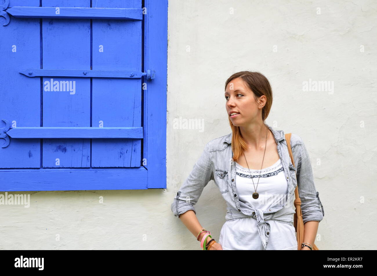 Young girl posing by the blue painted window shutters Stock Photo