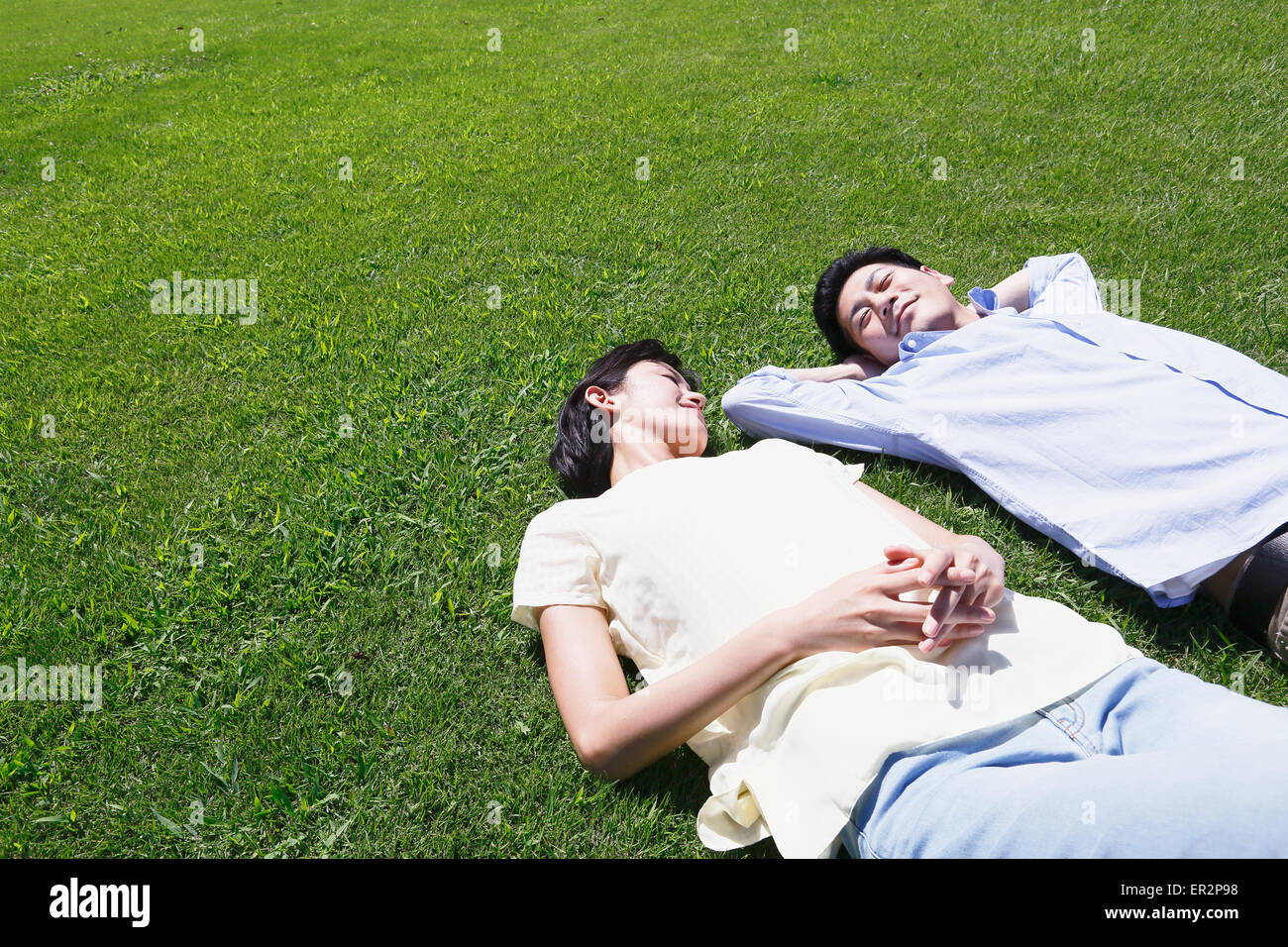 Happy Japanese couple laying on grass in a park Stock Photo - Alamy