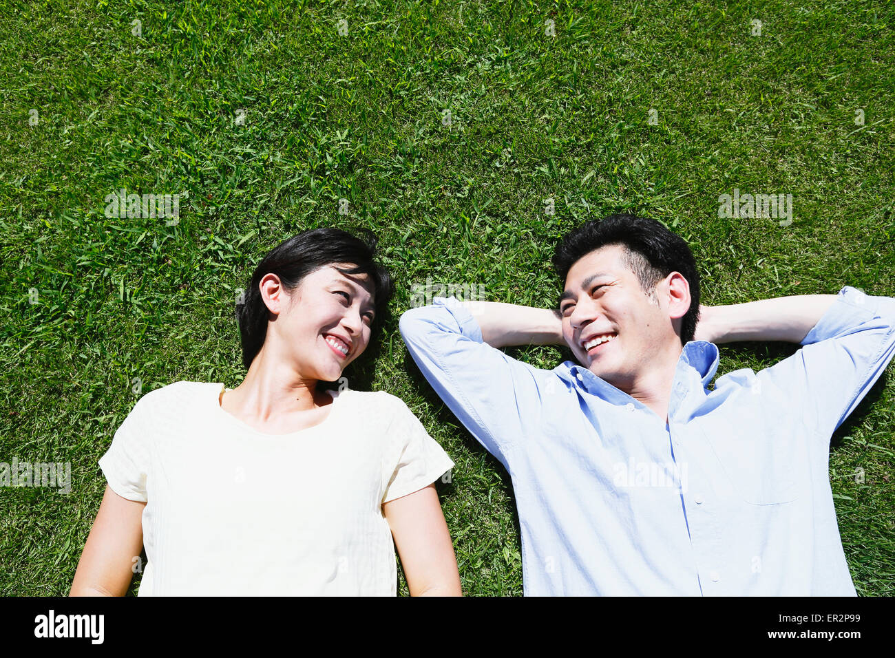 Happy Japanese couple laying on grass in a park Stock Photo - Alamy