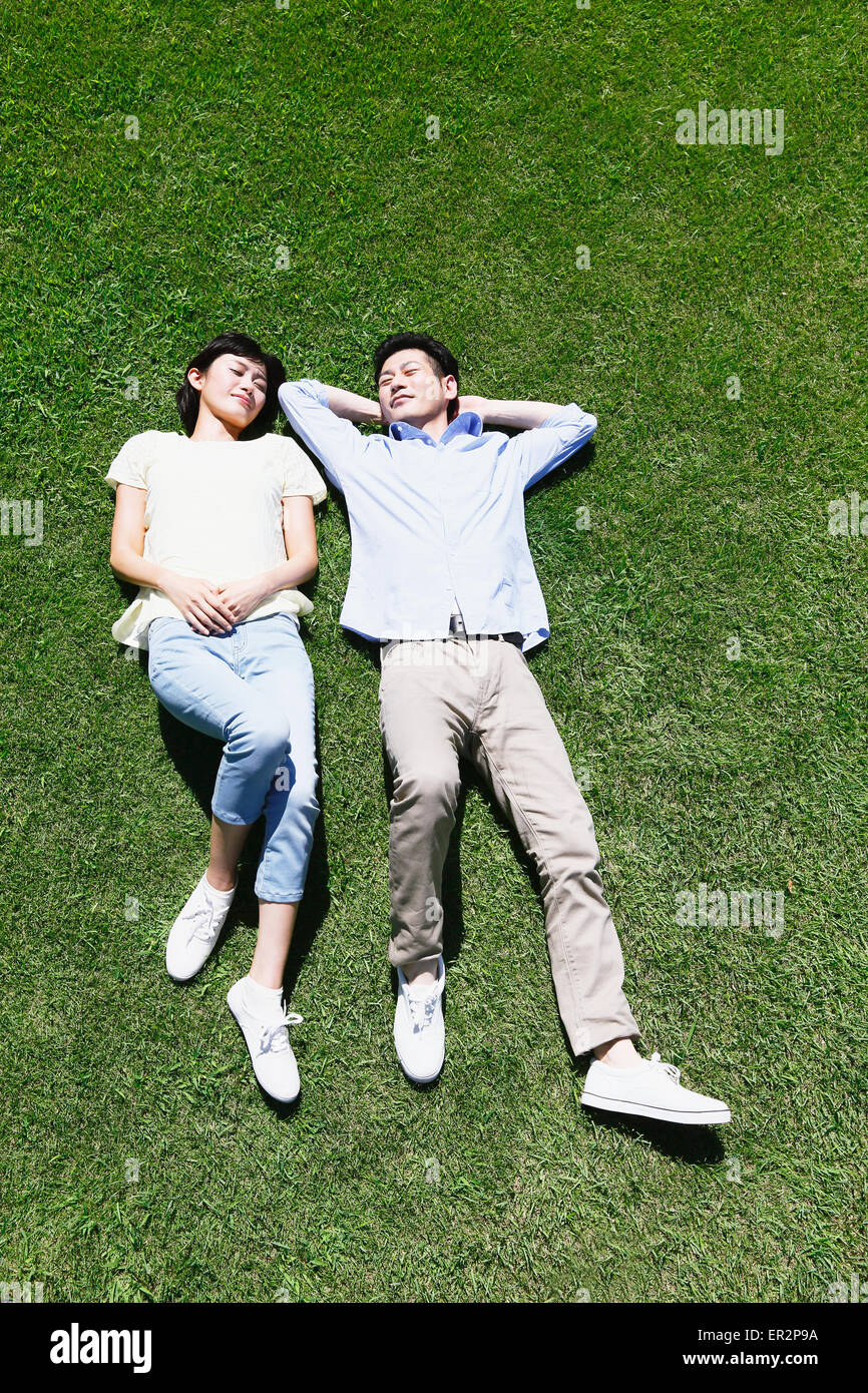 Happy Japanese couple laying on grass in a park Stock Photo - Alamy